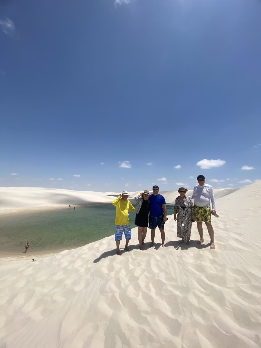 Grupo de viajantes sorrindo no alto de uma duna