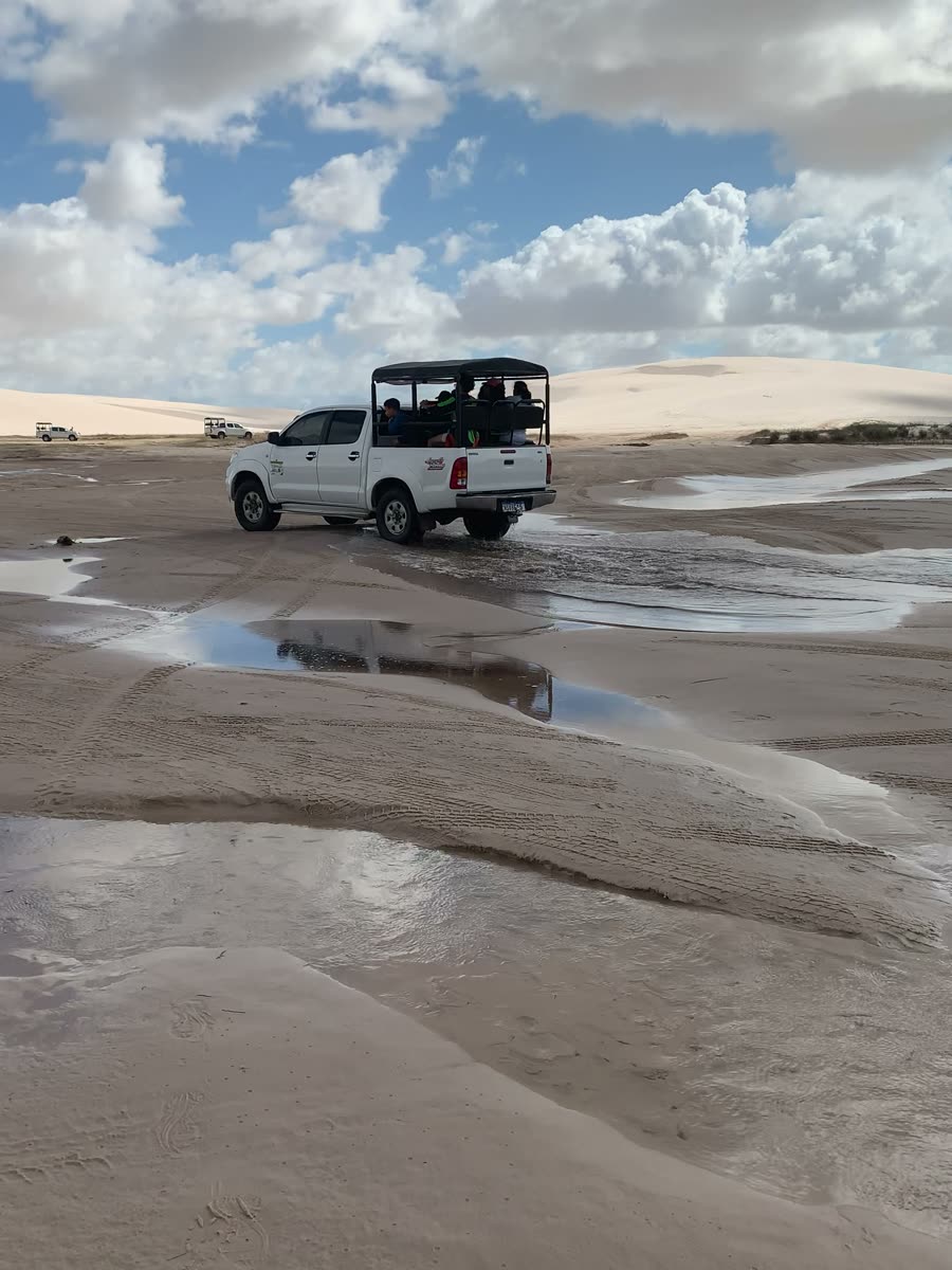 Jardineira 4x4 atravessando areia molhada a caminho das dunas